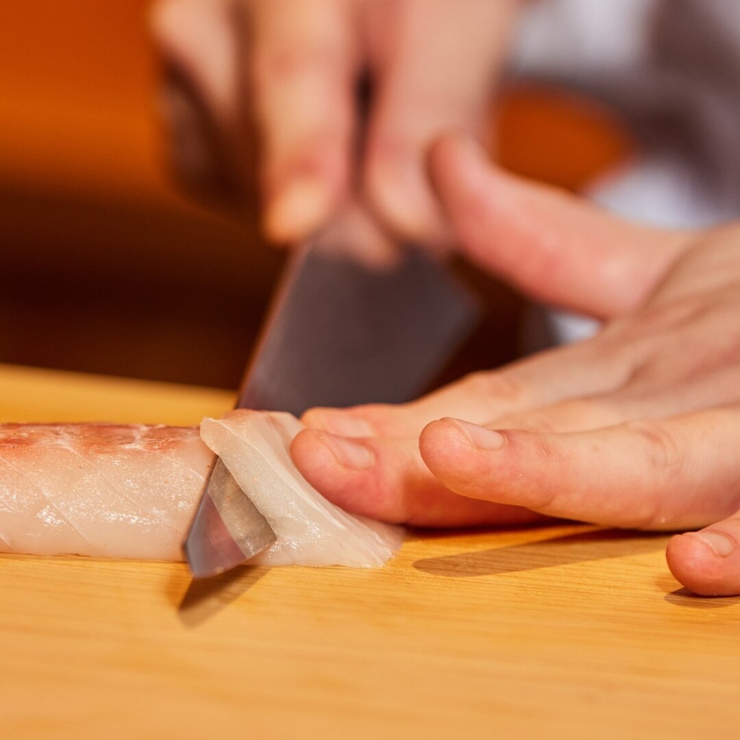 在新加坡 Omakase 餐厅，厨师正切下一片生鱼片。